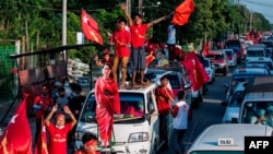 Supporters of the National League for Democracy (NLD) party celebrate with a cut-out figure of Myanmar state counsellor Aung San Suu Kyi in Yangon on November 10, 2020, as NLD officials said they were confident of a landslide victory in the weekend…