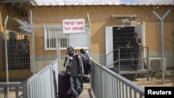 Des migrants africains, munis de bagages, quittent le centre de détention de Holot dans le désert du Néguev, dans le sud d'Israël, le 25 août 2015.