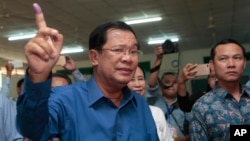 Cambodian Prime Minister Hun Sen of the Cambodian People's Party shows off his inked finger after voting in local elections at Takhmau polling station in Kandal province, southeast of Phnom Penh, Cambodia, Sunday, June 4, 2017. (AP Photo/Heng Sinith)