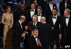 "La La Land" producer Jordan Horowitz (2L) speaks to stage manager Gary Natoli (C), reading the winners card, after "La La Land" mistakenly won the best picture instead of "Moonlight" at the 89th Oscars on February 26, 2017 in Hollywood, California.