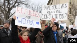 Protesters carry signs outside the White House during a protest to denounce President Donald Trump's executive order that blocks the arrival of all refugees to the United States, Sunday, Washington, Jan. 29, 2017. (Photo: S. Islam/VOA)