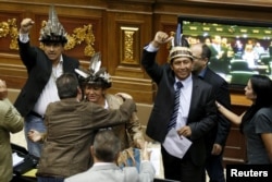FILE - Julio Ygarza, left, Nirma Guarulla, center, and Romel Guzamana, deputies of the Venezuelan coalition of opposition parties, celebrate after their swearing-in ceremony during a session of the National Assembly in Caracas, Jan. 6, 2016.