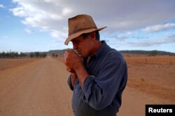 Farmer Ash Whitney lights a cigarette as he stands in the middle of a road that divides his drought-affected property, located west of the town of Gunnedah, in northwestern New South Wales in Australia, June 3, 2018.