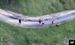 This photo made available by the U.S. Coast Guard shows residents near Utado Puerto Rico, waiting for supplies to be dropped from the air, Oct. 3, 2017.