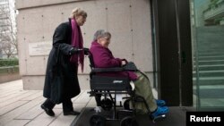 FILE - Gloria Taylor (R) enters the B.C Supreme Court with the help of Lee Carter, a fellow plaintiff in the case challenging the law regarding assisted-suicide in Vancouver, British Columbia on Dec. 1, 2011. Canada is announcing a new assisted-suicide law Thursday.