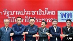 Pheu Thai Party leader Chonlanan Srikaew (3/R) and Bhumjaithai Party leader Anutin Charnvirakul (3/L) hold hands following a press conference at the Pheu Thai Party's headquarters in Bangkok on August 7, 2023. (Photo by MANAN VATSYAYANA / AFP)