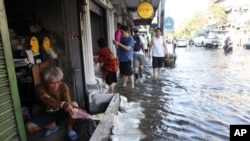 A man discards water from his house as water overflows from the Chao Phraya river to the street at Phranakhon district in Bangkok, October 24, 2011