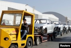 FILE - A worker transports car chassis at the Volkswagen plant in Puebla, Mexico, March 9, 2015.