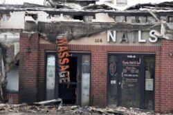 A sign hangs from the remains of a business after wildfires ripped through a development in Louisville, Colo., Dec. 31, 2021.