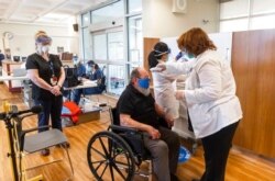 U.S. Air Force Veteran Robert Aucoin, 78, gets his temperature checked prior to receiving his COVID-19 vaccine dose at the Soldiers' Home in Holyoke, Mass., Dec. 29, 2020.