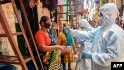 Petugas medis mengenakan alat pelindung diri (APD) melakukan tes Covid-19 dari pintu ke pintu di daerah kumuh Dharavi, Mumbai, India, 24 JUni 2020. (Foto: dok).
