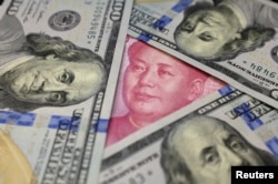 A U.S. 100 dollar bill featuring Benjamin Franklin is shown with a Chinese 100 yuan banknote with the late Chinese Chairman Mao Zedong, Jan. 21, 2016.