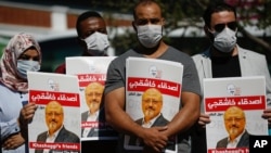 People hold posters of slain Saudi journalist Jamal Khashoggi, near the Saudi Arabian Consulate in Istanbul, marking the two-year anniversary of his death, Oct. 2, 2020.