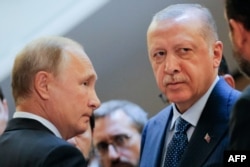 Russian President Vladimir Putin, left, and Turkish President Recep Tayyip Erdogan wait to enter a hall during their meeting at the Bocharov Ruchei residence in the Black Sea resort of Sochi on Sept. 17, 2018.