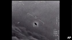 FILE - Image from video provided by the Department of Defense labelled Gimbal, from 2015, an unexplained object is seen at center as it is tracked as it soars high along the clouds, traveling against the wind. 