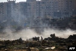 Seorang pria Palestina mengambil barang-barang dari tempat pembuangan sampah di atas puing-puing bangunan di kamp al-Bureij di Jalur Gaza tengah pada 2 Juni 2024. (Foto: AFP)