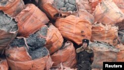 Seorang tentara Korea Utara berjaga di depan karung-karung berisi bijih mineral di tepi Sungai Yalu, dekat Kota Sinuiju Korea Utara yang berbatasan dengan Kota Dandong di China, 28 Desember 2011. (Foto:Dok)