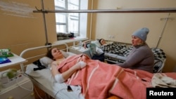 Seorang kenalan menjenguk Marina Klimenko (28), dan Lyudmila Antonenko (46) di rumah sakit di Donetsk, Ukraina yang dikuasai Rusia, 22 Januari 2024. Keduanya terluka akibat serangan militer Ukraina. (REUTERS/Alexander)