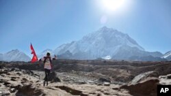 A Nepalese runs with his national flag during a marathon to mark the first conquest of Mount Everest, at Lobuche, near Everest base camp, Nepal, Monday, May 29, 2017. 