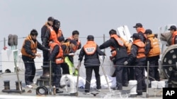 Para polisi penjaga pantai memeriksa jenasah korban kapl feri "Sewol" yang tenggelam di perairan dekat Jindo, selatan Seoul, Korea Selatan (20/4).