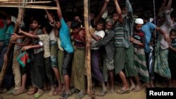 Rohingya refugees jostle as they line up for a blanket distribution under heavy rainfall at the Balukhali camp near Cox's Bazar, Bangladesh, Dec. 11, 2017.