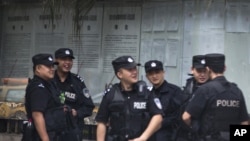 FILE - Chinese policemen huddle near the Chengdu Intermediate People's Court in Chengdu in southwest China's Sichuan province.