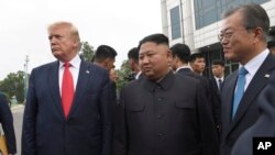 Presiden Donald Trump, pemimpin Korea Utara Kim Jong Un dan Presiden Korea Selatan Moon Jae-in, berjalan bersama di desa perbatasan Panmunjom di Zona Demiliterisasi, Korea Selatan, Minggu, 30 Juni 2019. (Foto: AP/Susan Walsh)