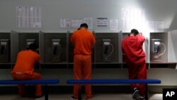 FILE - Detainees talk on telephones at the Adelanto ICE Processing Center in Adelanto, Calif., Aug. 28, 2019. 
