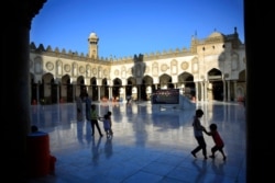 FILE - Egyptian children play as their family awaits the afternoon prayer on the first Friday of the holy month of Ramadan inside the Al-Azhar mosque, in Cairo, Egypt, June 19, 2015.