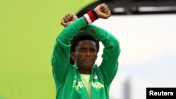FILE - Silver medalist Feyisa Lilesa of Ethiopia crosses his wrists in an attempt to draw global attention to recent deadly protests in his home region, Oromia, after the men's marathon at the 2016 Summer Olympics.