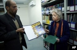 FILE - Nancy Hatch Dupree and her colleague show an archived paper of the Taliban regime during an interview with The Associated Press at the Afghanistan Center in Kabul University, Dec. 9, 2014.
