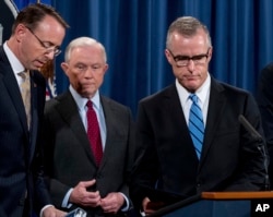 FILE - Then-acting FBI Director Andrew McCabe, right, accompanied by then-Attorney General Jeff Sessions, center, and Deputy Attorney General Rod Rosenstein, takes the podium at a news conference at the Department of Justice, Washington, July 20, 2017.