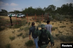 A U.S. border patrol agent escorts men being detained after entering the United States by crossing the Rio Grande river from Mexico, in Roma, Texas, May 11, 2017.