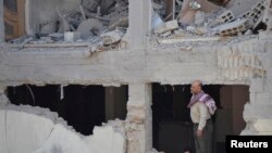 A man and boys inspect a site hit by what activists said was shelling by forces loyal to Syria's President Bashar al-Assad, Duma, Damascus, Sept. 4, 2013.