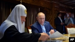 Russian President Vladimir Putin, with Russian Orthodox Patriarch Kirill, left, speak in the library of the Russian monastery St. Panteleimon at Karyes, on Mount Athos, Greece, May 28, 2016.