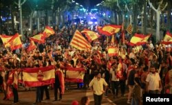 Pro unity demonstrators wave Spanish and Catalan flags during a protest after the Catalan regional parliament declared independence from Spain in Barcelona, Spain, Oct. 27, 2017.