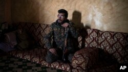 Dia Hassakeh, 45, a fighter in the Kurdish-led U.S-backed Syrian Democratic Forces, looks out of a building in Baghouz, Syria, Feb. 18, 2019.
