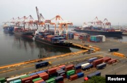 FILE - Cargo vessels wait to unload containers, while docked at the port in Manila, Aug. 20, 2014.