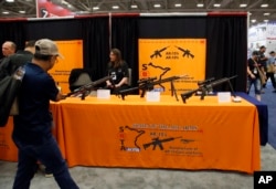 FILE - Attendees walk by a display of AR-15s and AR-10s at the National Rifle Association convention in Dallas, May 4, 2018.