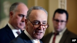 FILE - Senate Minority Leader Chuck Schumer of N.Y., center, accompanied by Sen. Bob Casey, D-Pa., at left, speaks on Capitol Hill, Feb. 6, 2018 in Washington.