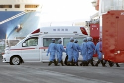Members of Japan Self Defense Forces walk into the quarantined cruise ship Diamond Princess in the Yokohama Port Sunday, Feb. 9, 2020, in Yokohama, Japan.