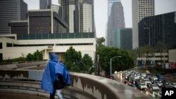 Jerry Rodriguez, left, shares a rain poncho with his girlfriend, Lilyana Del Villar, Feb. 10, 2017, in downtown Los Angeles. A strong storm is forecast to hit Southern California this weekend.
