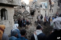People gather at the site of a Saudi-led airstrike near Yemen's Defense Ministry complex in Sanaa, Yemen, Saturday, Nov. 11, 2017.
