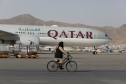 FILE - A Taliban soldier patrols on a bike in front of a Qatar Airways flight at the international airport in Kabul, Afghanistan, Sept. 10, 2021. (West Asia News Agency via Reuters)