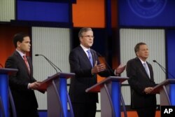Jeb Bush, center, speaks as Marco Rubio, right and John Kasich listen during a Republican presidential primary debate in Des Moines, Iowa, Jan. 28, 2016.