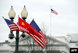 FILE - A lamp post is adorned with a Chinese national flag in between two U.S. flags in front of the White House in Washington, D.C., Jan. 17, 2011, in honor of a visit to the U.S. by Chinese President Xi Jinping. Departing from established protocol, President-elect Donald Trump has not committed himself to continue the "One China" policy followed by previous administrations.