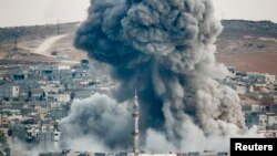 Smoke rises over Syrian town of Kobani after an airstrike, as seen from the Mursitpinar border crossing on the Turkish-Syrian border in the southeastern town of Suruc, Sanliurfa province, Oct. 18, 2014.