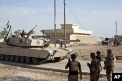 Iraqi special forces soldiers use radio communication as a tank rolls down an alley in the village of Bazwaya, some 8 kilometers from the center of Mosul, Iraq, Oct. 31, 2016.