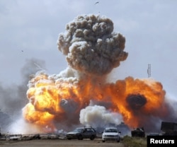 Vehicles belonging to forces loyal to Libyan leader Moammar Gadhafi explode after an airstrike by coalition forces, along a road between Benghazi and, March 20, 2011.