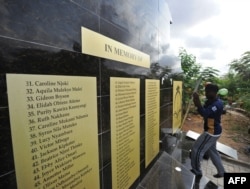 Workers mount a plaque as they work on the memorial for the victims of last year's terrorist attack that killed 148 people at the campus of Garissa University College, on April 2, 2016 in Garissa, ahead of the inaugural Garissa marathon.